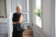 A lady carrying a leather and canvas handcrafted small black tote travel bag.