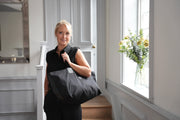 A lady carrying a leather and canvas handcrafted black tote travel bag.