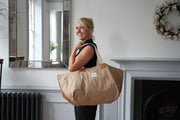 A lady carrying risdon and risdon canvas and leather market bag made in england.