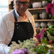 Male florist wearing handcrafted, black denim apron with removable straps; made in Britain.