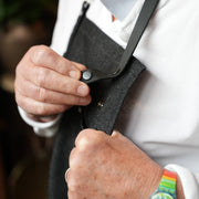 Man wearing handcrafted, black denim apron with removable straps; made in Britain.