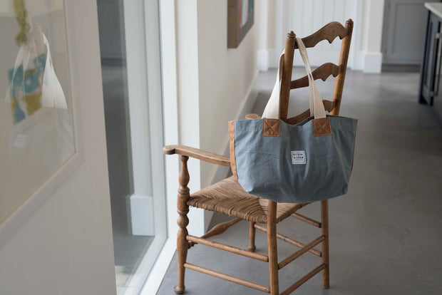 A grey canvas market bag hanging on a chair