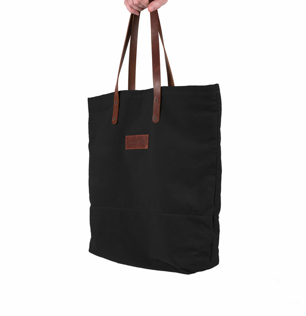 A handcrafted black canvas totebag with leather straps.