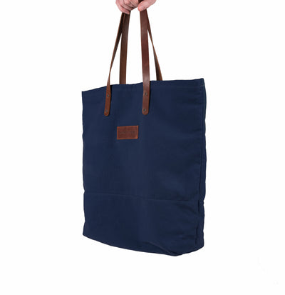 A handcrafted blue canvas totebag with leather straps.