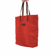 A handcrafted red canvas totebag with leather straps.
