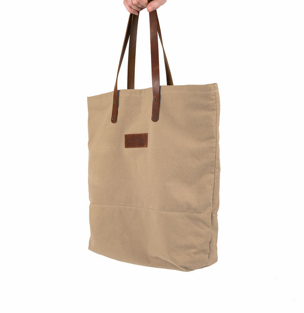 A handcrafted tan canvas totebag with leather straps.