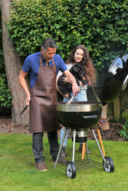 Man grilling with barbecue wearing a handcrafted brown leather apron with matching leather straps: made in Britain.