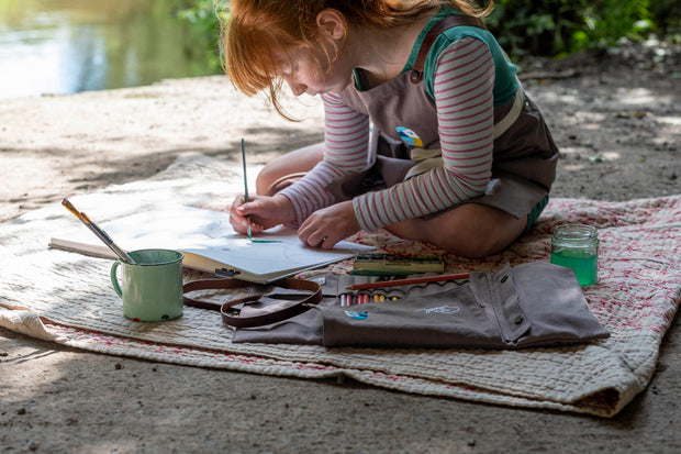 A child drawing with a grey canvas handcrafted artist roll. Features leather strap and an image of a bird.