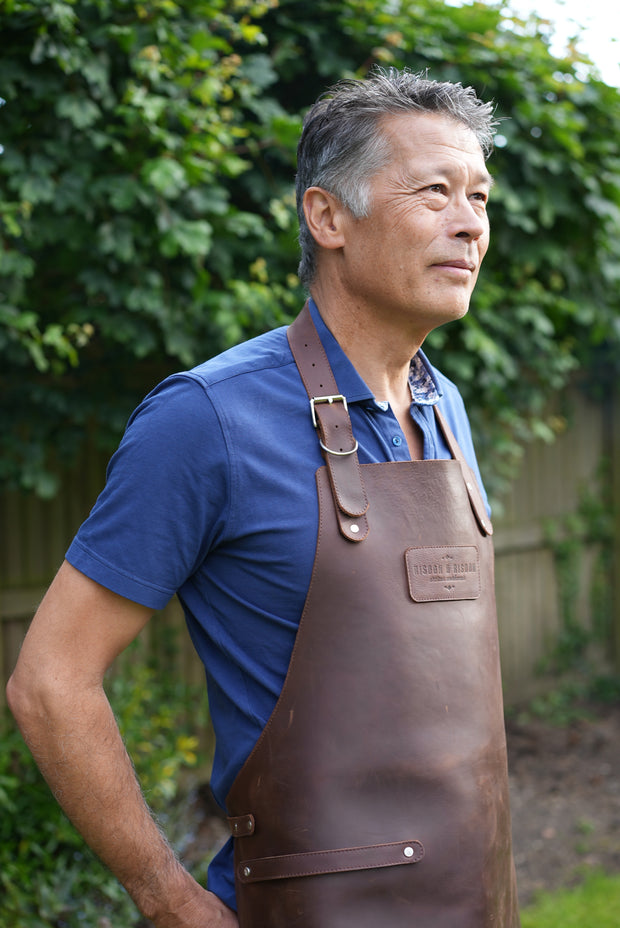 Man wearing handcrafted brown leather apron with matching leather straps: made in Britain.