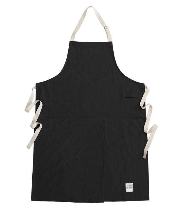 Handcrafted, black canvas apron with white straps; made in Britain.