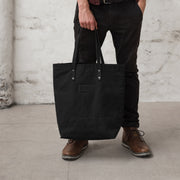 Man carrying a black handmade leather and canvas tote bag. British made.