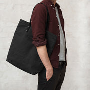 Man carrying a black handmade leather and canvas tote bag. British made.