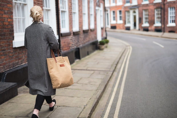 A parson carrying a handcrafted tan canvas totebag with leather straps.