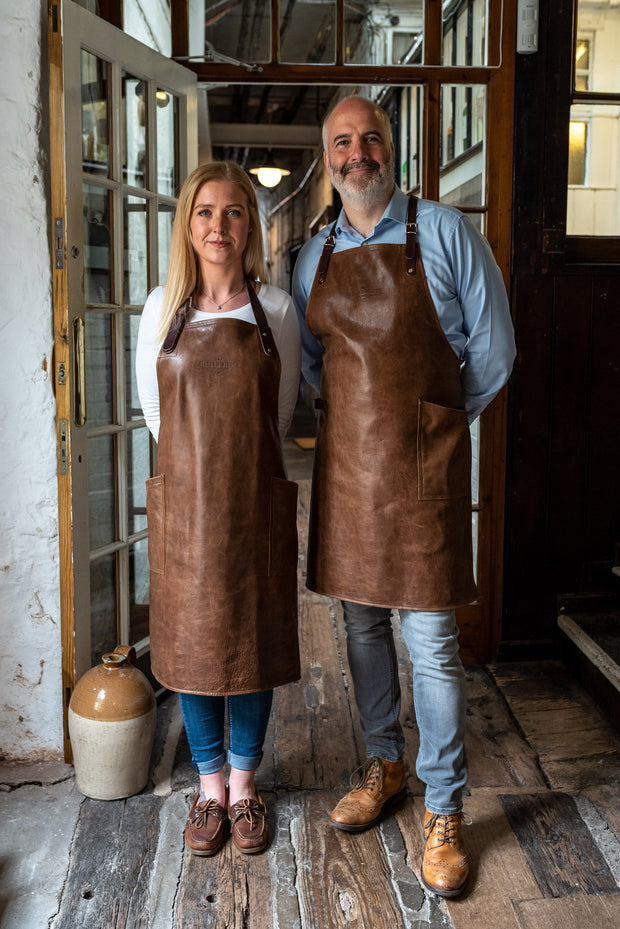 Two people wearing an all leather handcrafted apron with removeable straps. made in britan