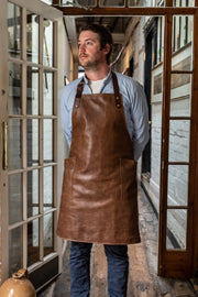 A person wearing an all leather handcrafted apron with removeable straps. made in britan