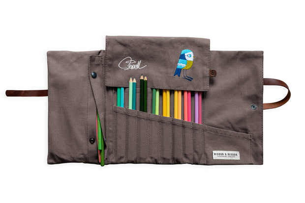 A grey canvas handcrafted artist roll. Features leather strap and an image of a bird.