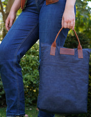 A lady carrying a leather and denim kneeler cushion