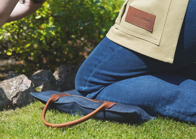 A lady kneeling on a handcrafted leather and denim kneeler cushion